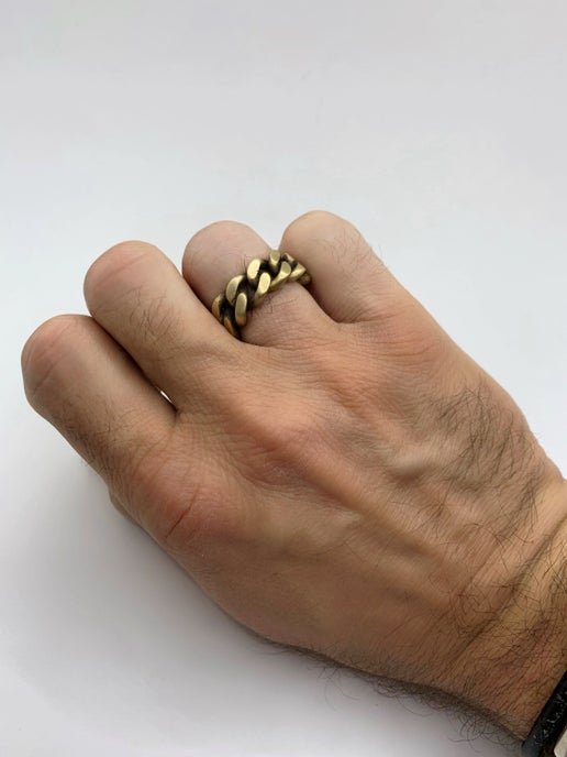 Hand wearing a gold chain ring on a white background
