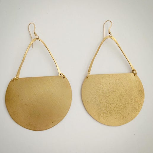 Gold earrings with circular designs on a white background