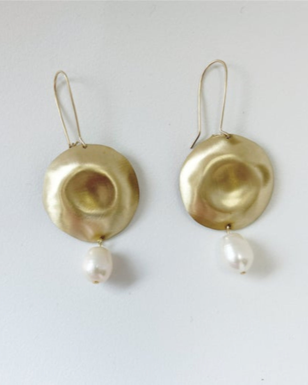 Gold earrings with pearl drops on a white background