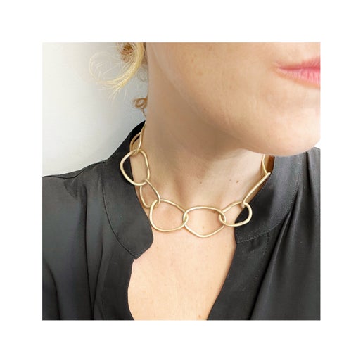 Gold link necklace worn by a person on a white background
