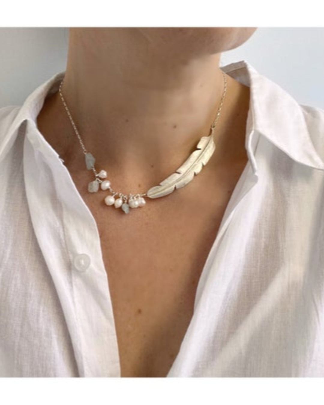 Bronze necklace with pearls and bronze  accents worn by a person in a white shirt.