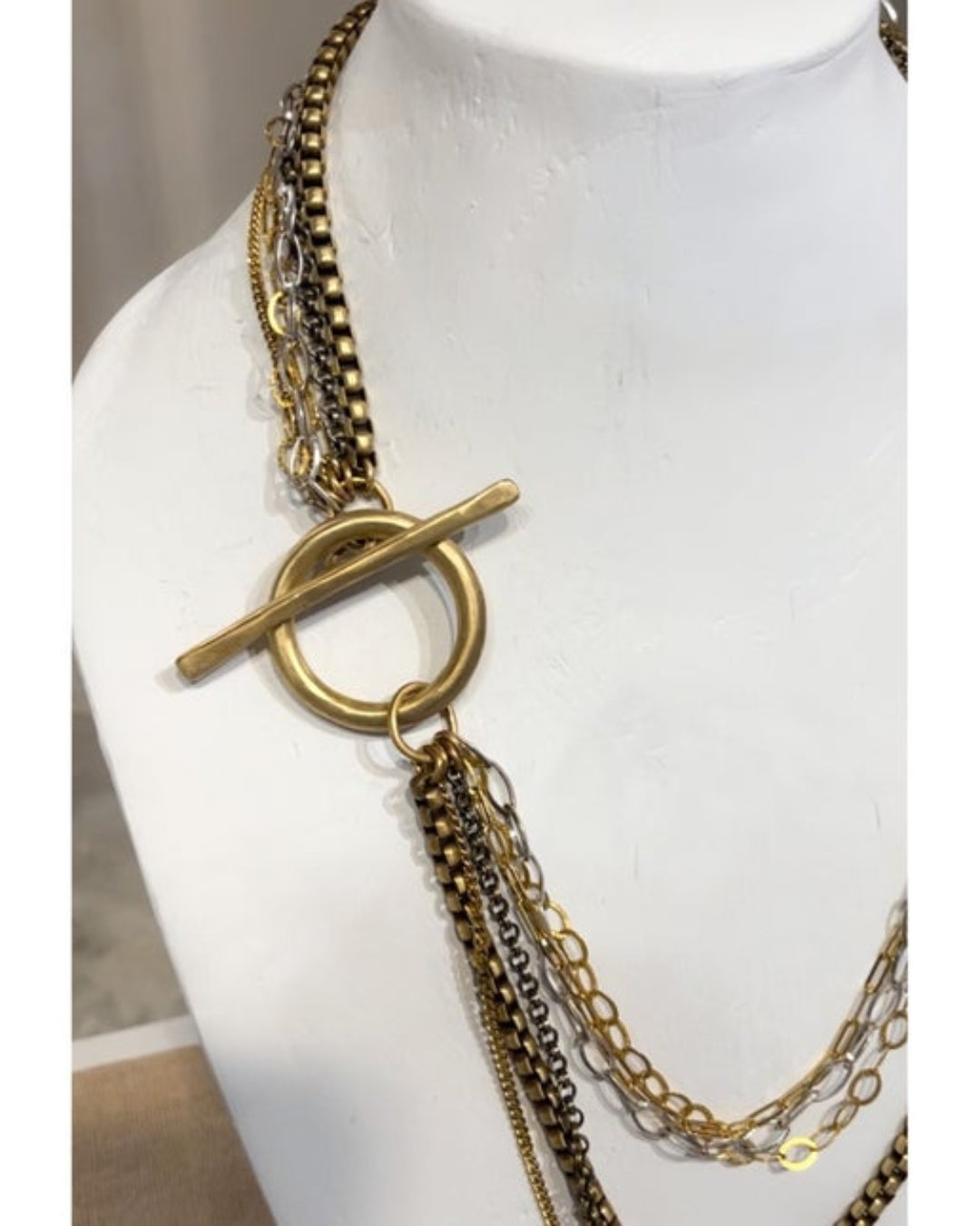 Gold multi-strand necklace with a large toggle on a mannequin bust