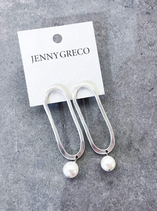 Silver hoop earrings with pearl drops on a Jenny Greco card against a gray background