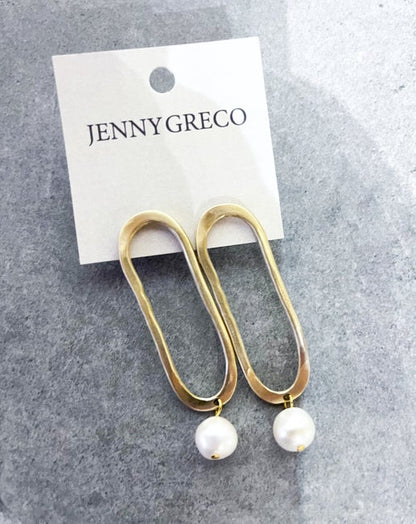Gold hoop earrings with pearl drops on a Jenny Greco card against a gray background