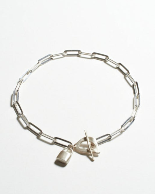 Silver paperclip necklace with a lock charm on a white background