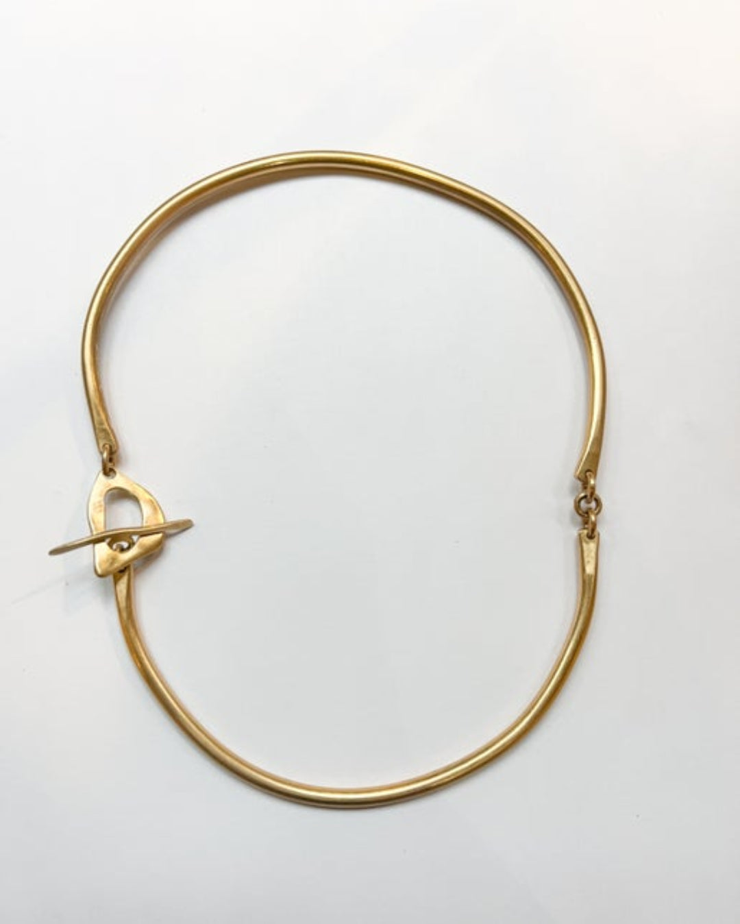 Gold necklace with toggle closure on a light gray background