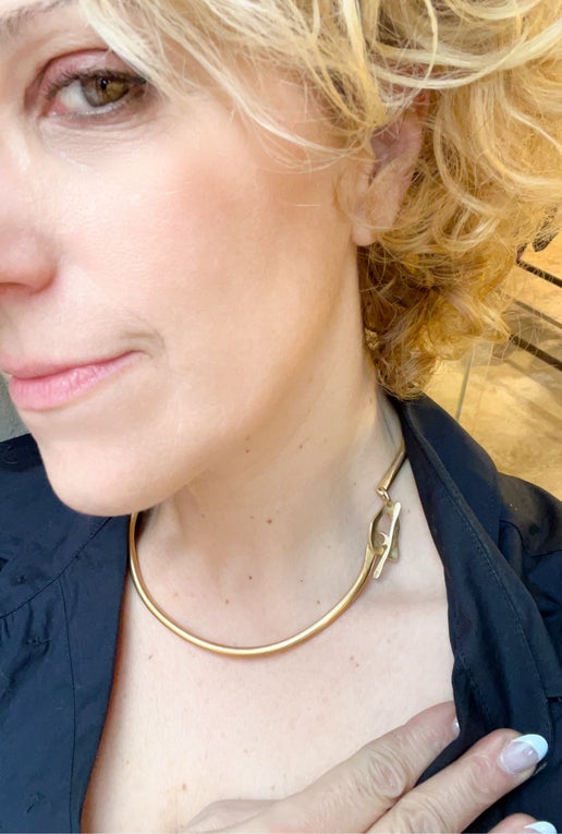 Close-up of a person wearing a gold necklace with a blurred background