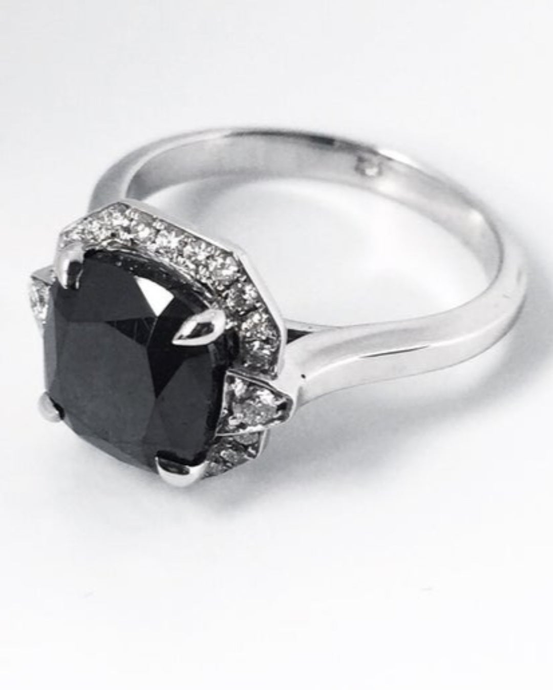 Silver ring with a large black diamond and smaller diamonds on a white background