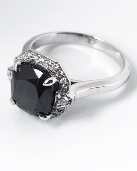 Silver ring with a large black diamond and smaller diamonds on a white background