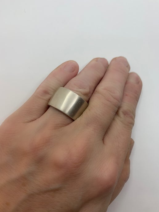Hand wearing a silver ring on a white background