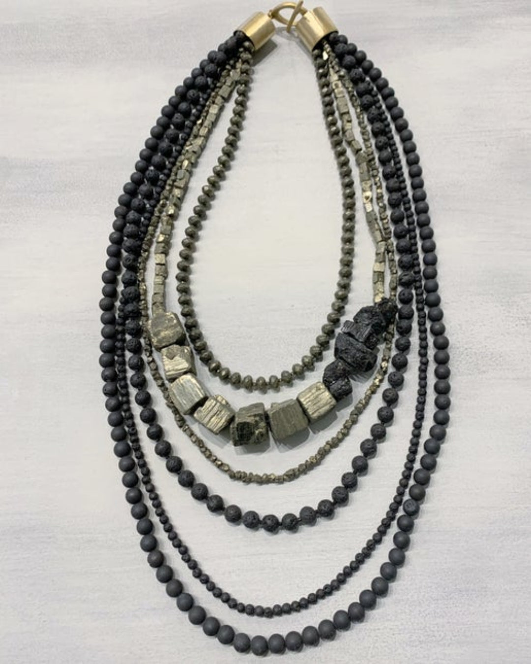 Multi-strand beaded necklace with black and gray beads on a white background