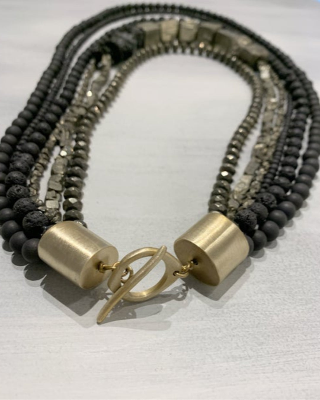 Multistrand beaded necklace with gold clasp on a neutral background