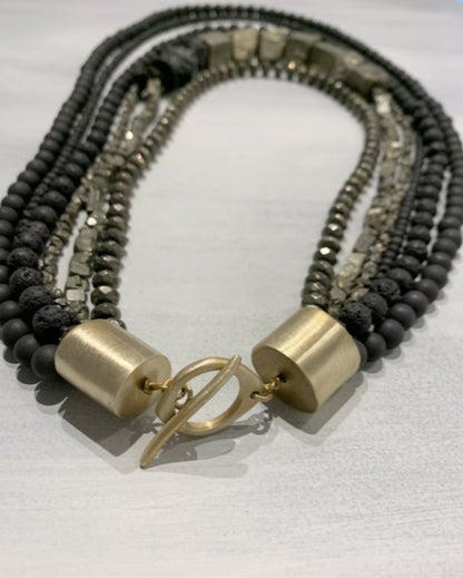 Multistrand beaded necklace with gold clasp on a neutral background
