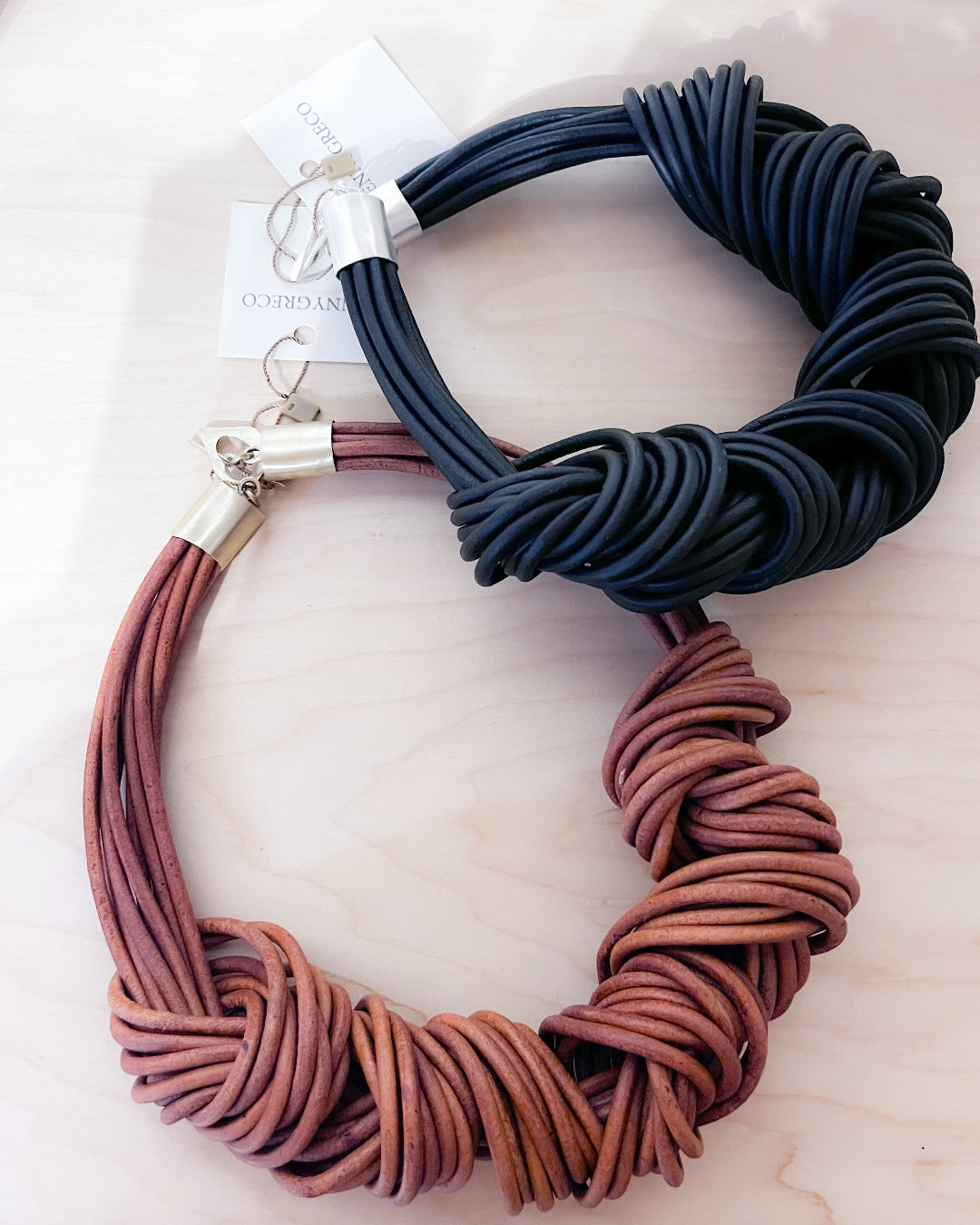 Two multistrand leather knotted necklaces, one blue and one brown, on a light background.