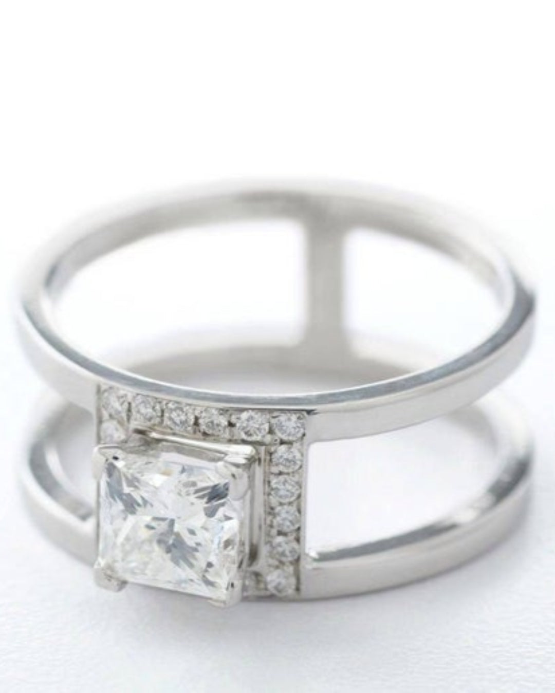 Silver ring with a large square-cut gemstone and smaller diamonds on a white background