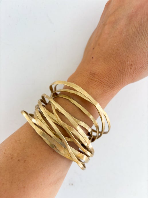 Gold multistrand bracelet on a wrist against a white background