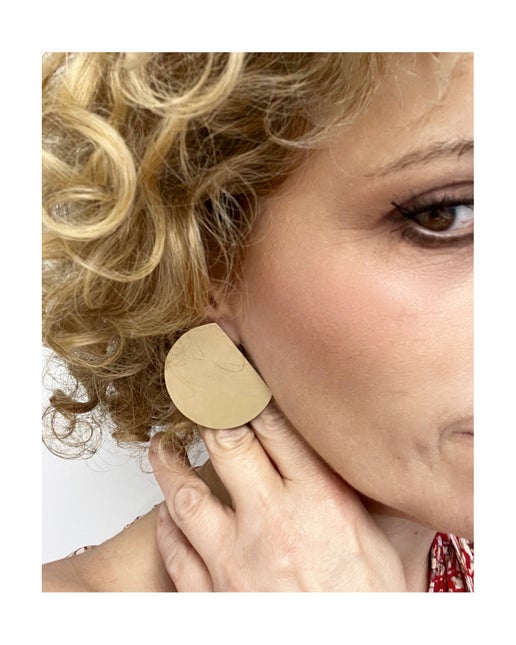 Woman wearing a bronze earring with a plain background