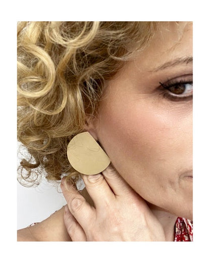 Woman wearing a bronze earring with a plain background