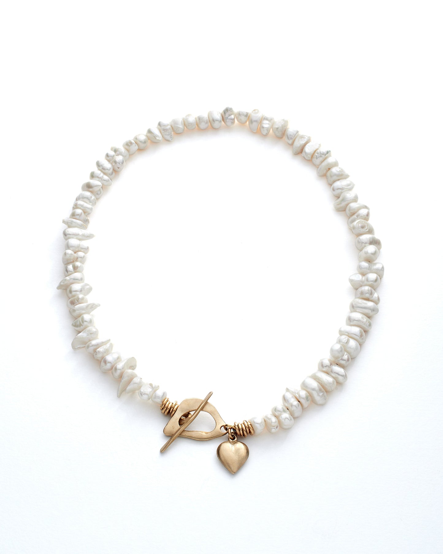 Pearl necklace with bronze clasp and heart charm on a white background