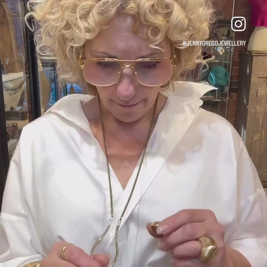 Woman in a white shirt wearing bold gold jewellery in a retail store setting