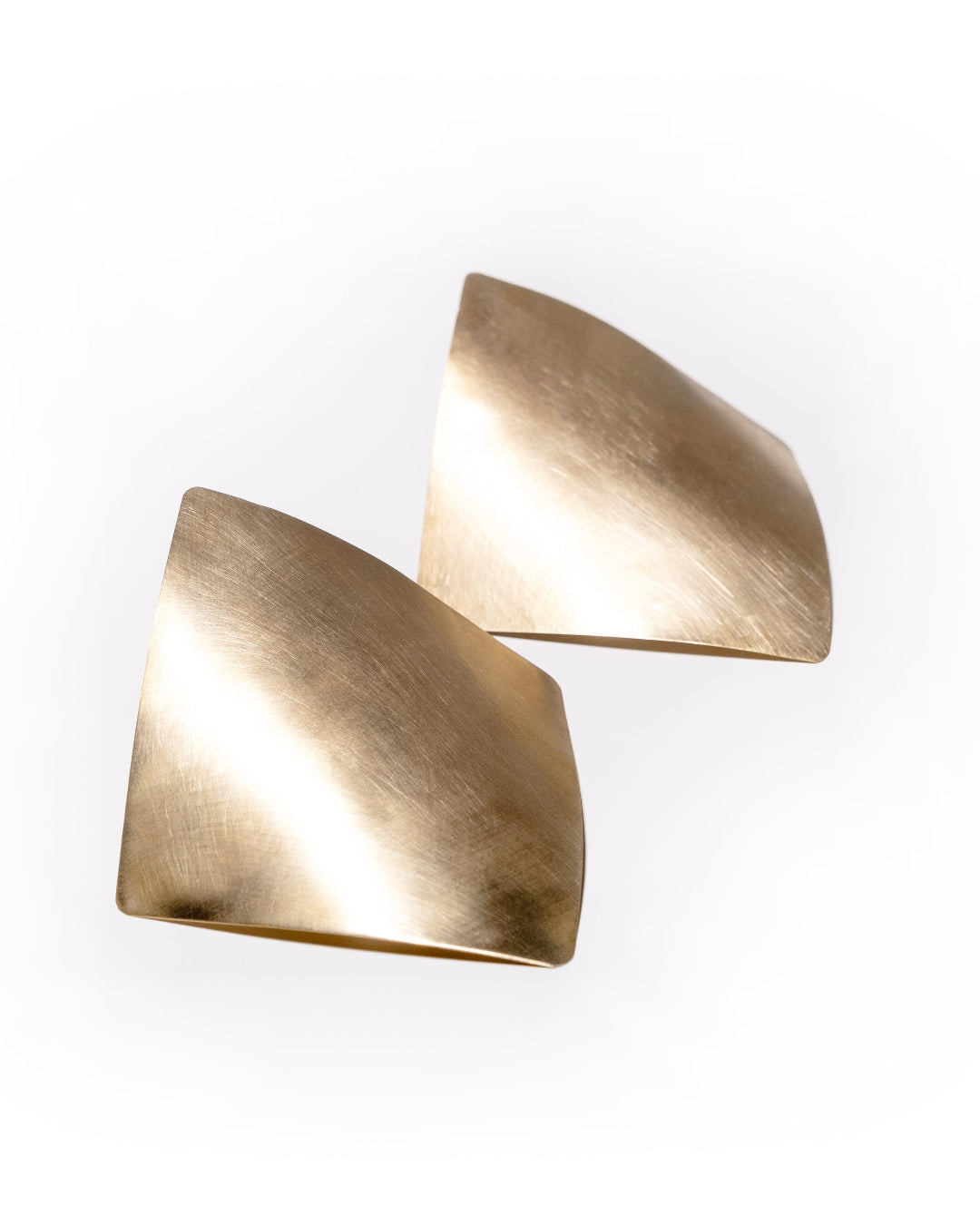 Pair of curved gold triangular earrings on a white background