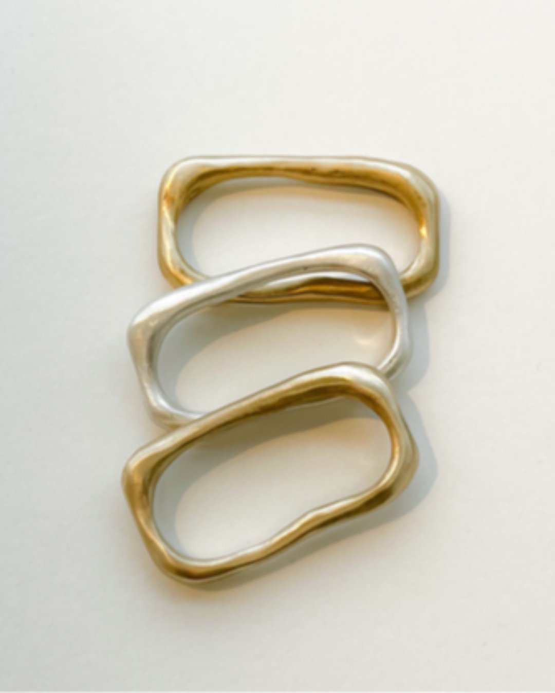 Three gold and silver rings stacked on a light gray background