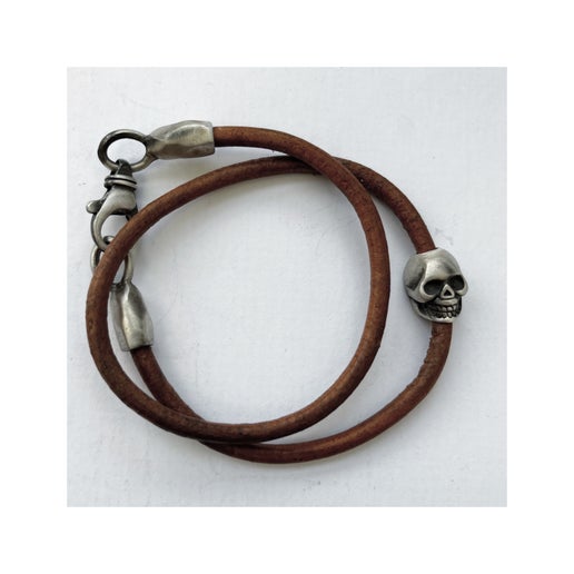 Brown double wrap leather bracelet with silver skull charm and clasp on a white background