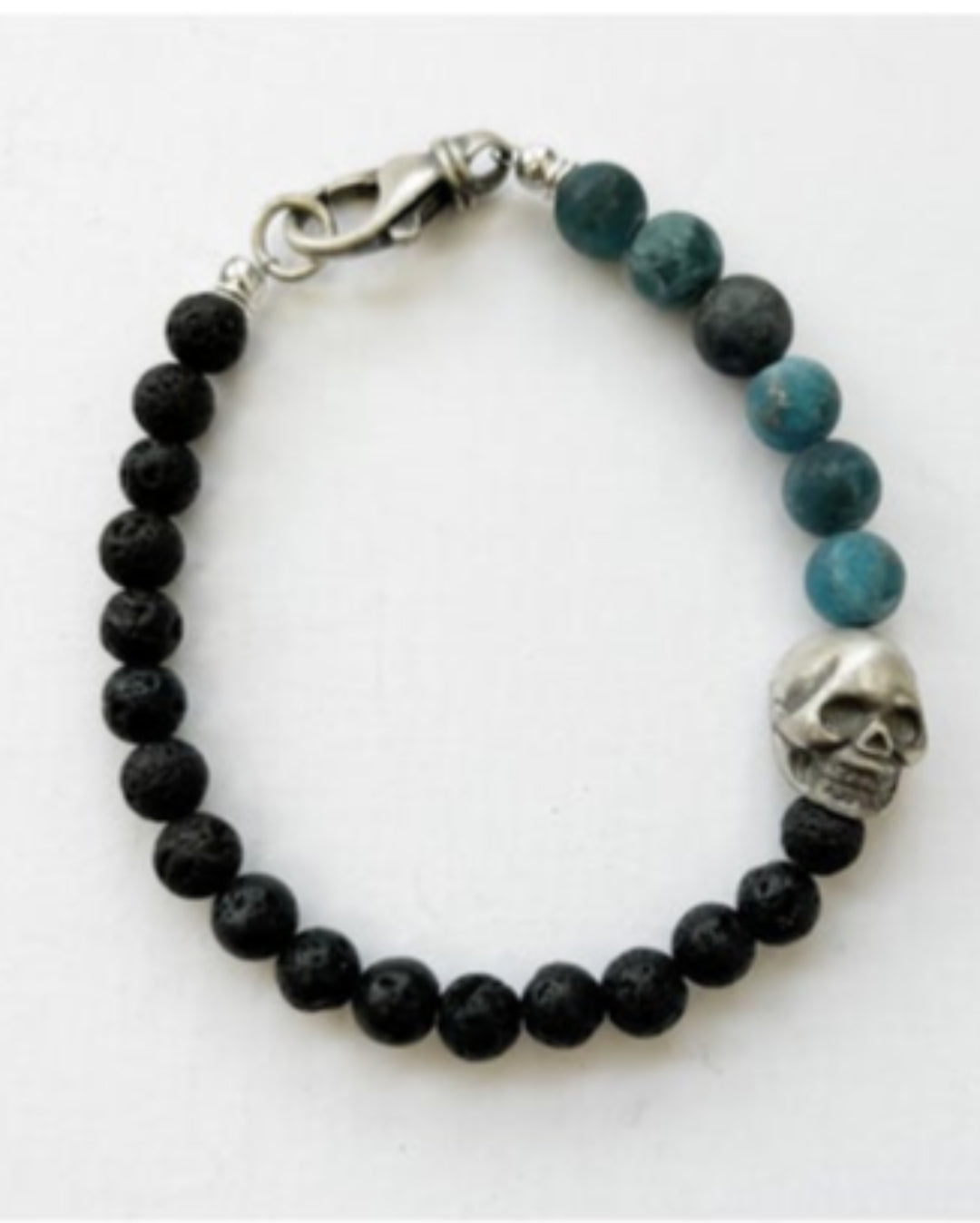 Beaded bracelet with black and blue beads and a silver skull charm on a white background