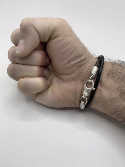 Hand wearing a double wrap leather bracelet with a silver clasp on a white background