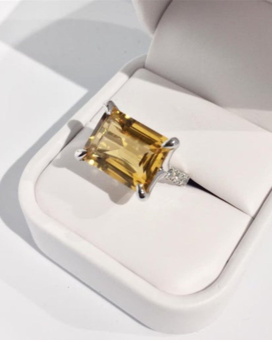 Ring with a yellow gemstone  and diamond band in a white box