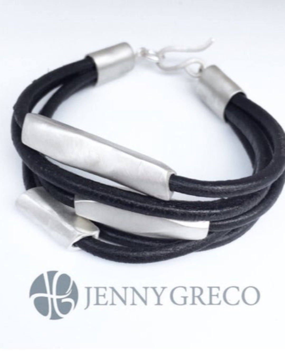Black leather multistrand bracelet with silver metal details on a white background, featuring the brand 'Jenny Greco'.