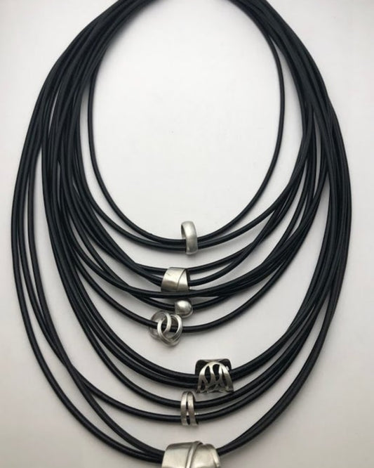 Multistrand black leather necklace with silver details on a light gray background