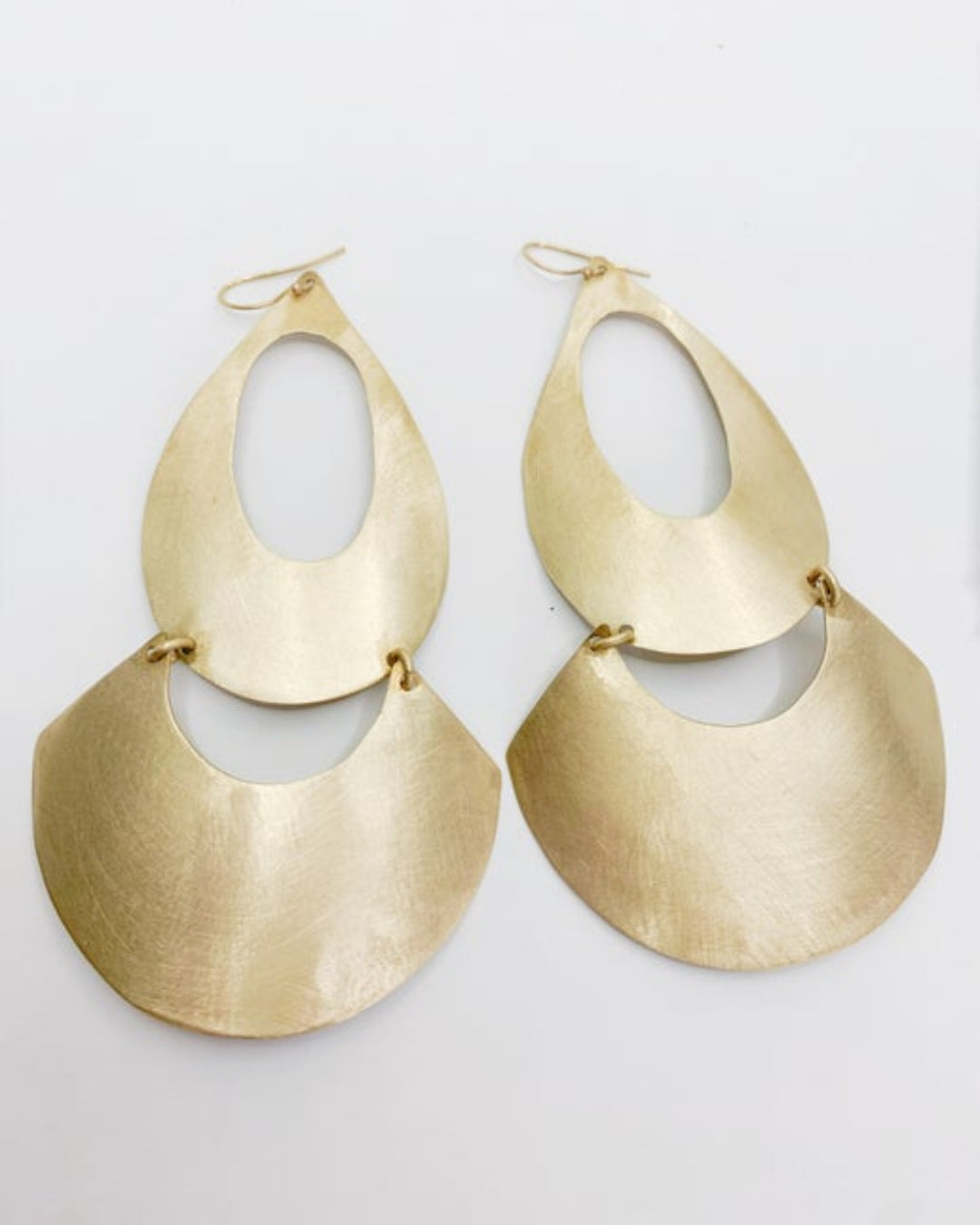 Pair of geometric gold earrings on a light gray background