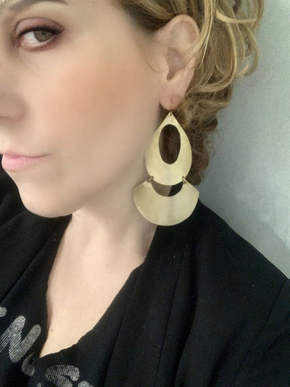 Close-up of a person wearing geometric gold earring with a neutral background